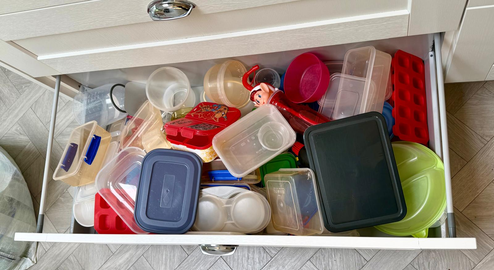 Food container drawer before organising, with tubs and lids piled loose