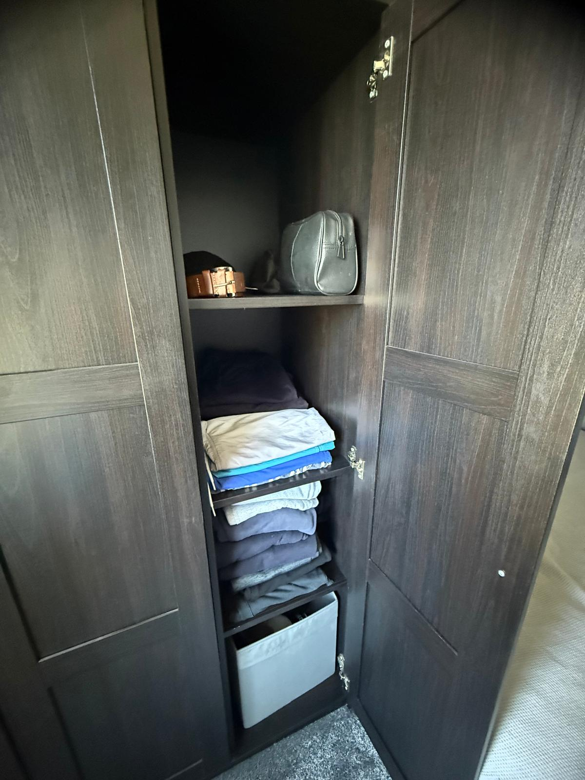 Wardrobe shelves after organising, with folded clothes and a labelled storage box