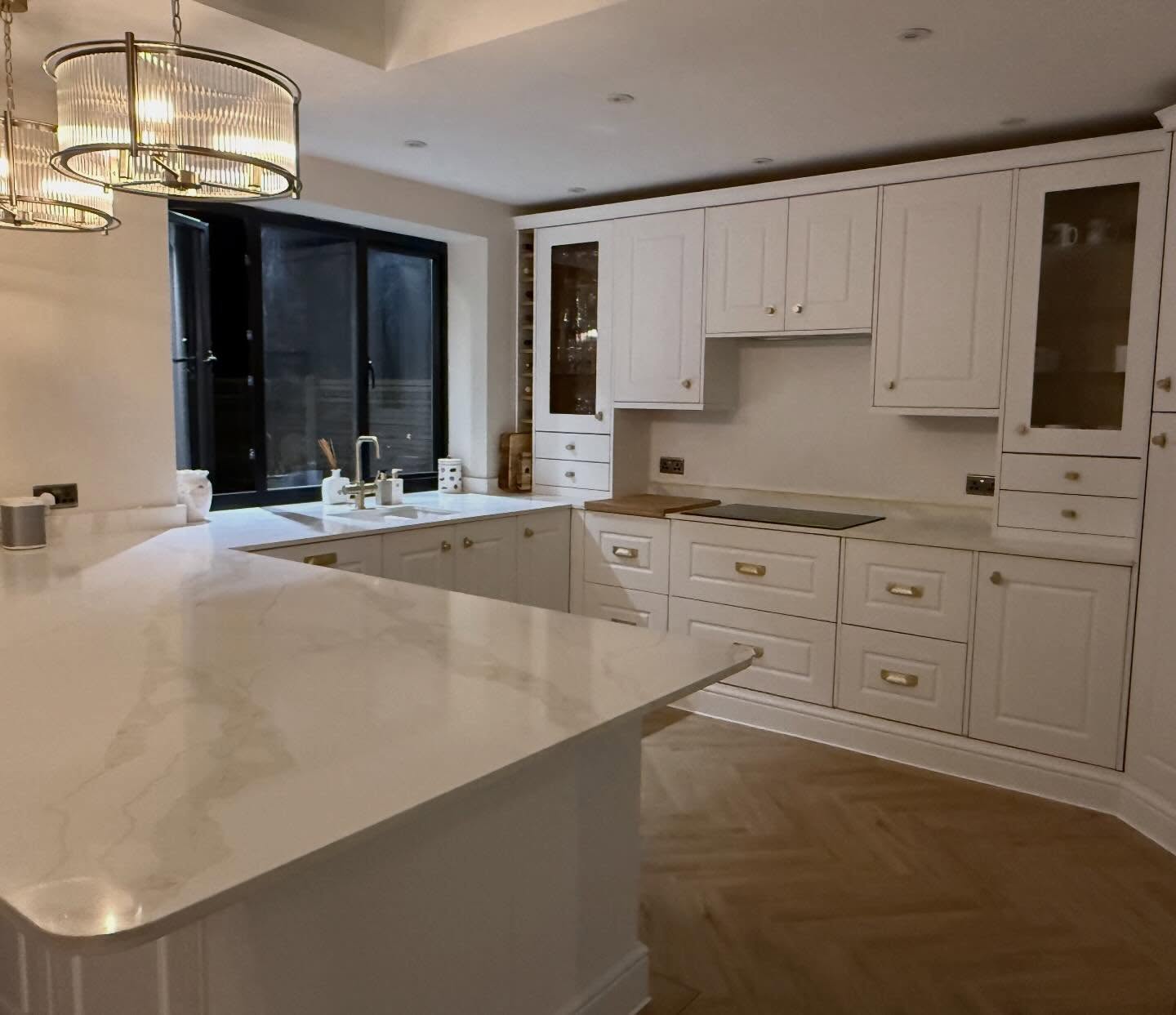 Decluttered kitchen with clear marble worktops, cream cabinetry and brass pendant lighting