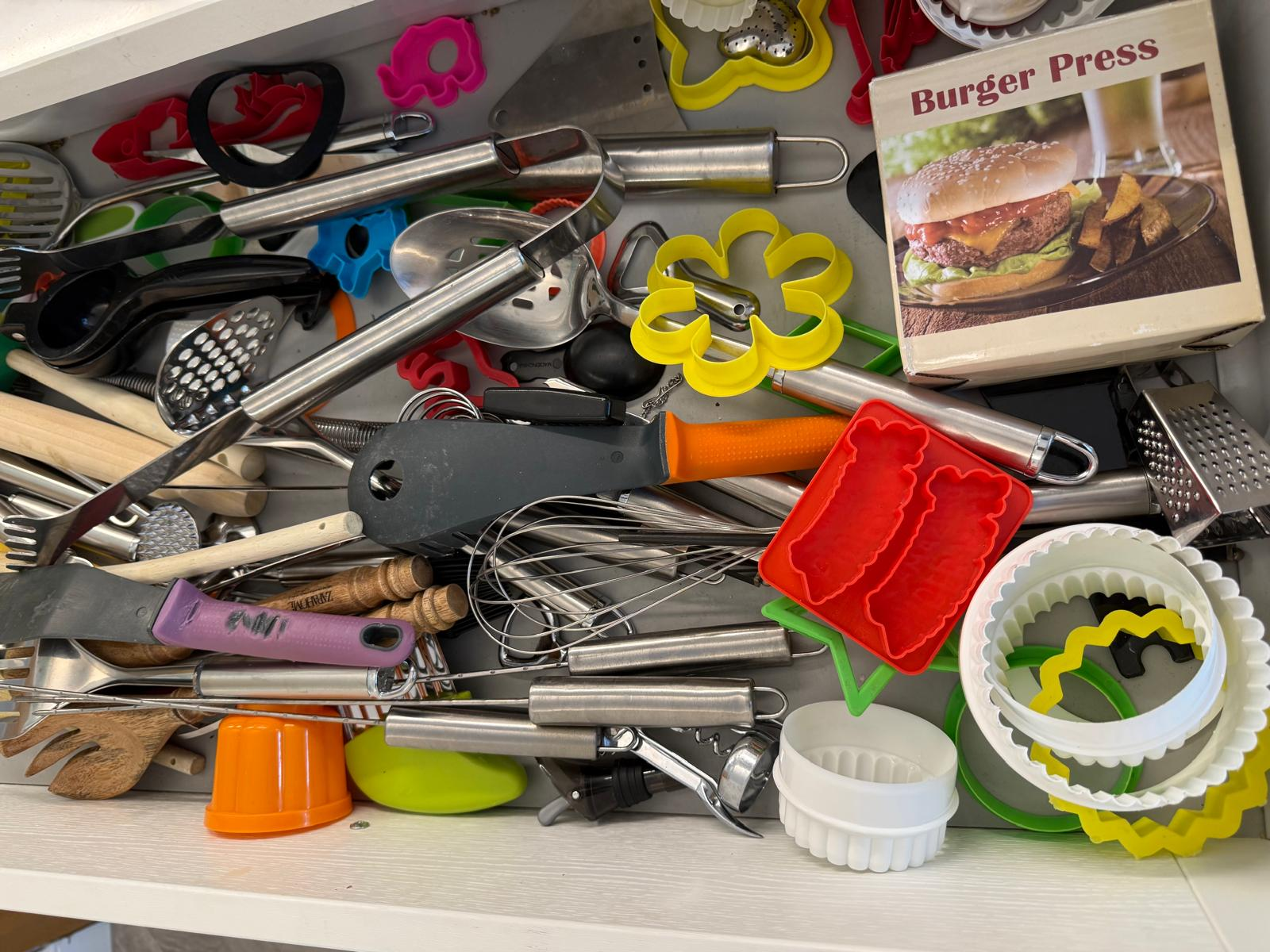 Kitchen utensil drawer before organising, with tools and cutters jumbled together