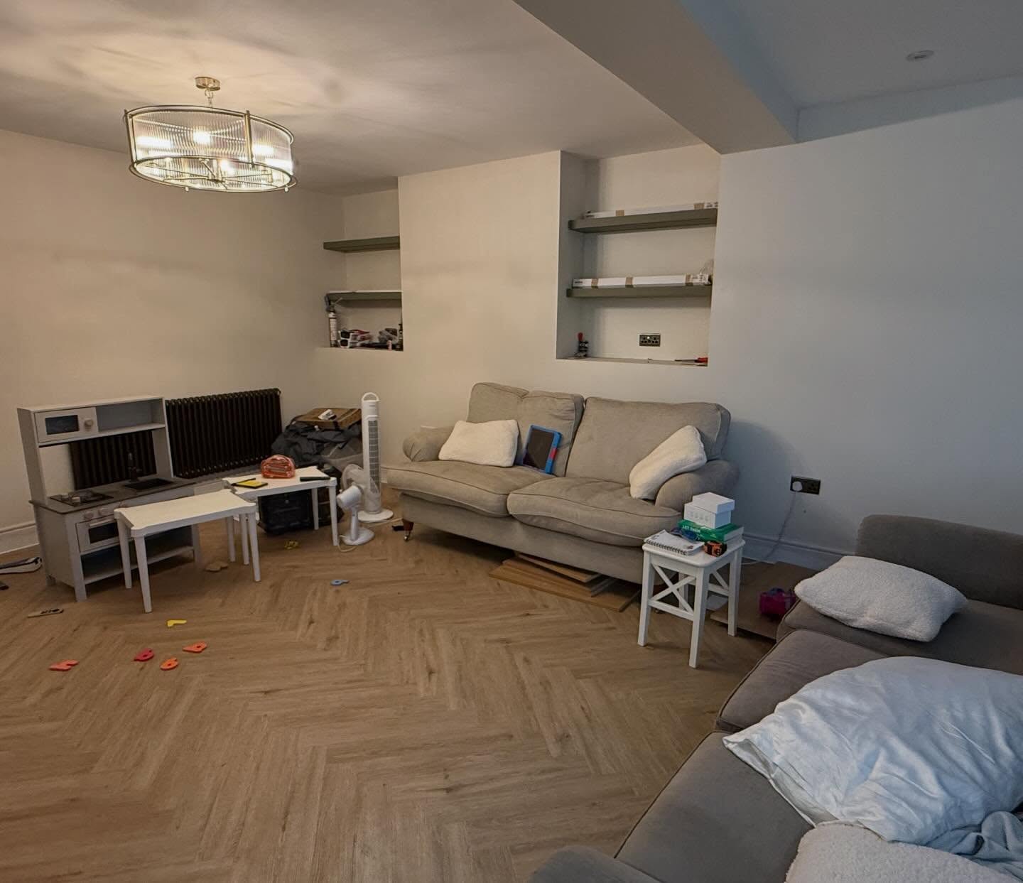 Living room before organising, with toys, boxes and bedding across the floor