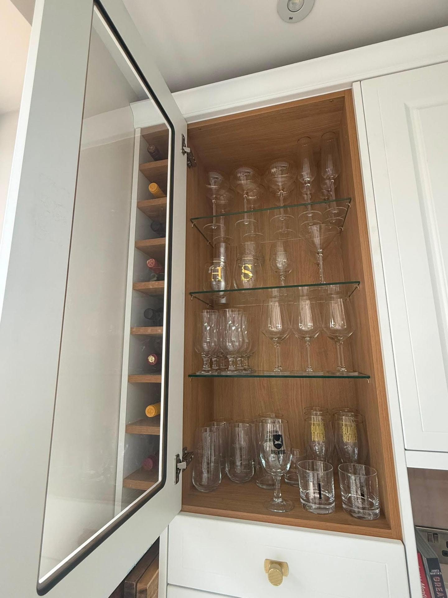 Organised glassware cabinet with wine, champagne and tumbler glasses arranged by type