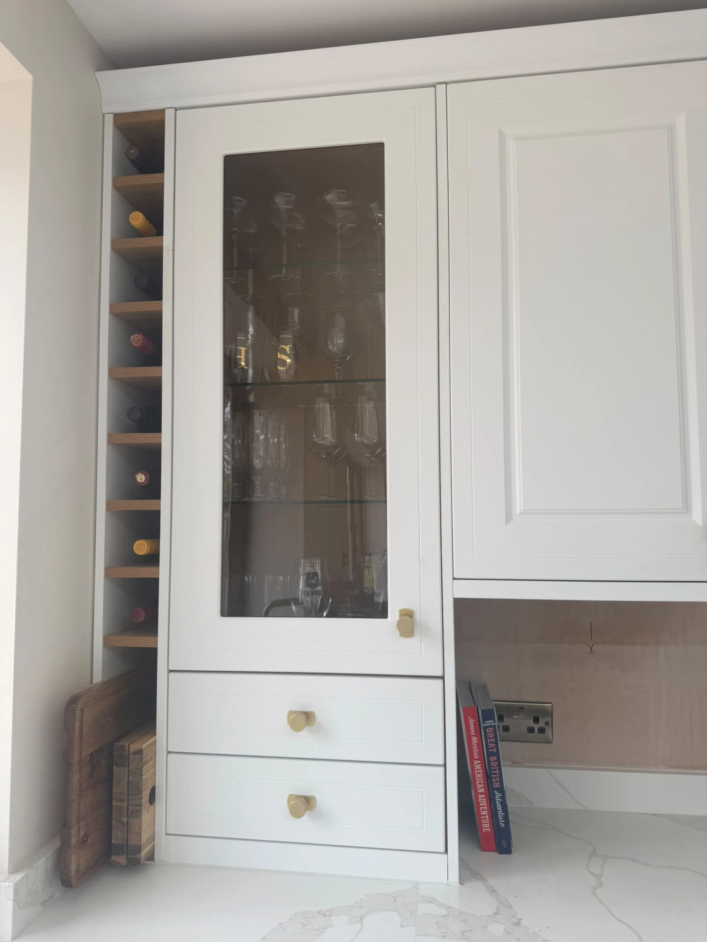 Glass-fronted kitchen cabinet with glassware arranged neatly beside a built-in wine rack
