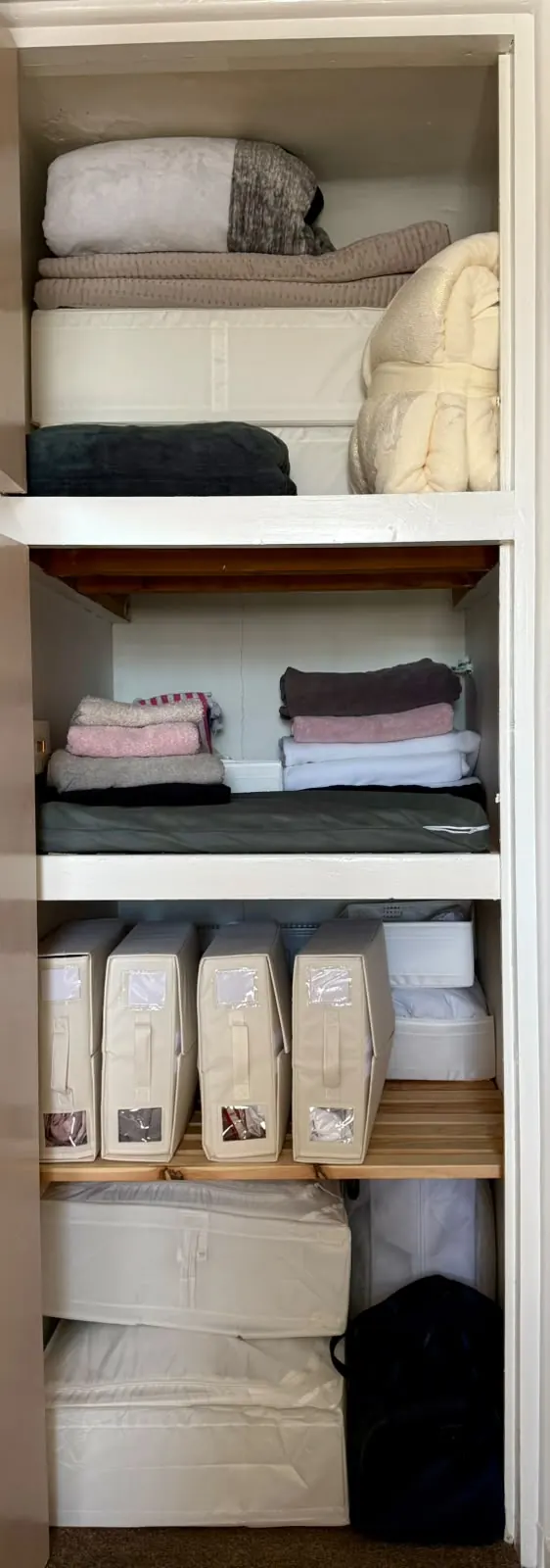 Linen cupboard after organising, with folded bedding and towels and labelled storage bags
