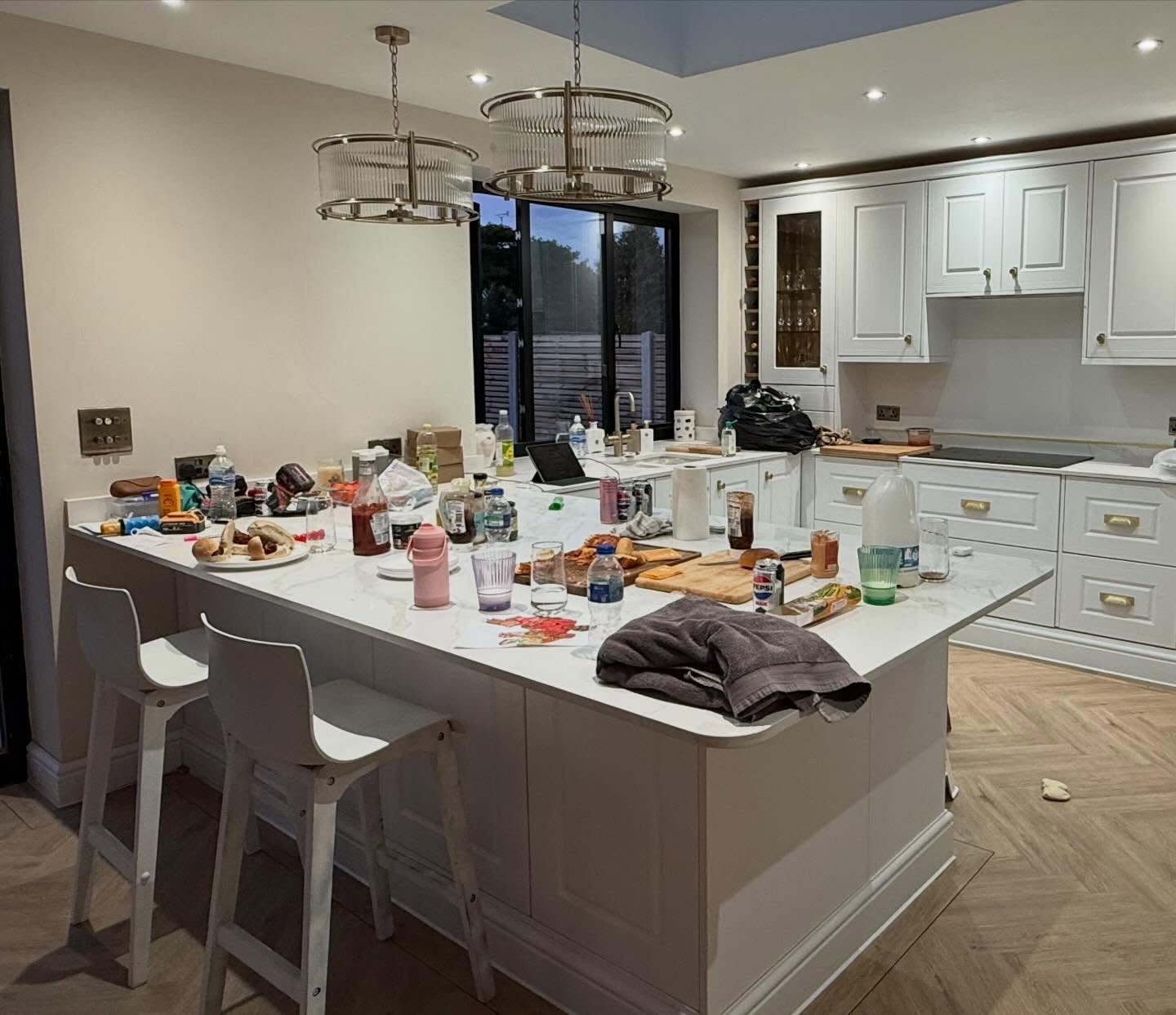 Kitchen island before organising, covered with bottles, plates and clutter
