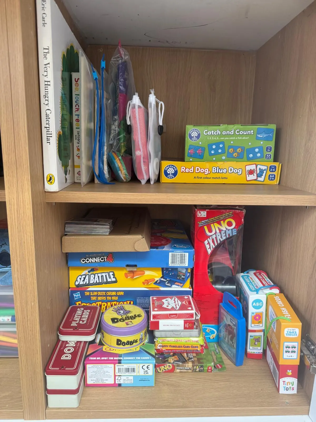 Games cupboard after organising, with books upright and games neatly stacked by size