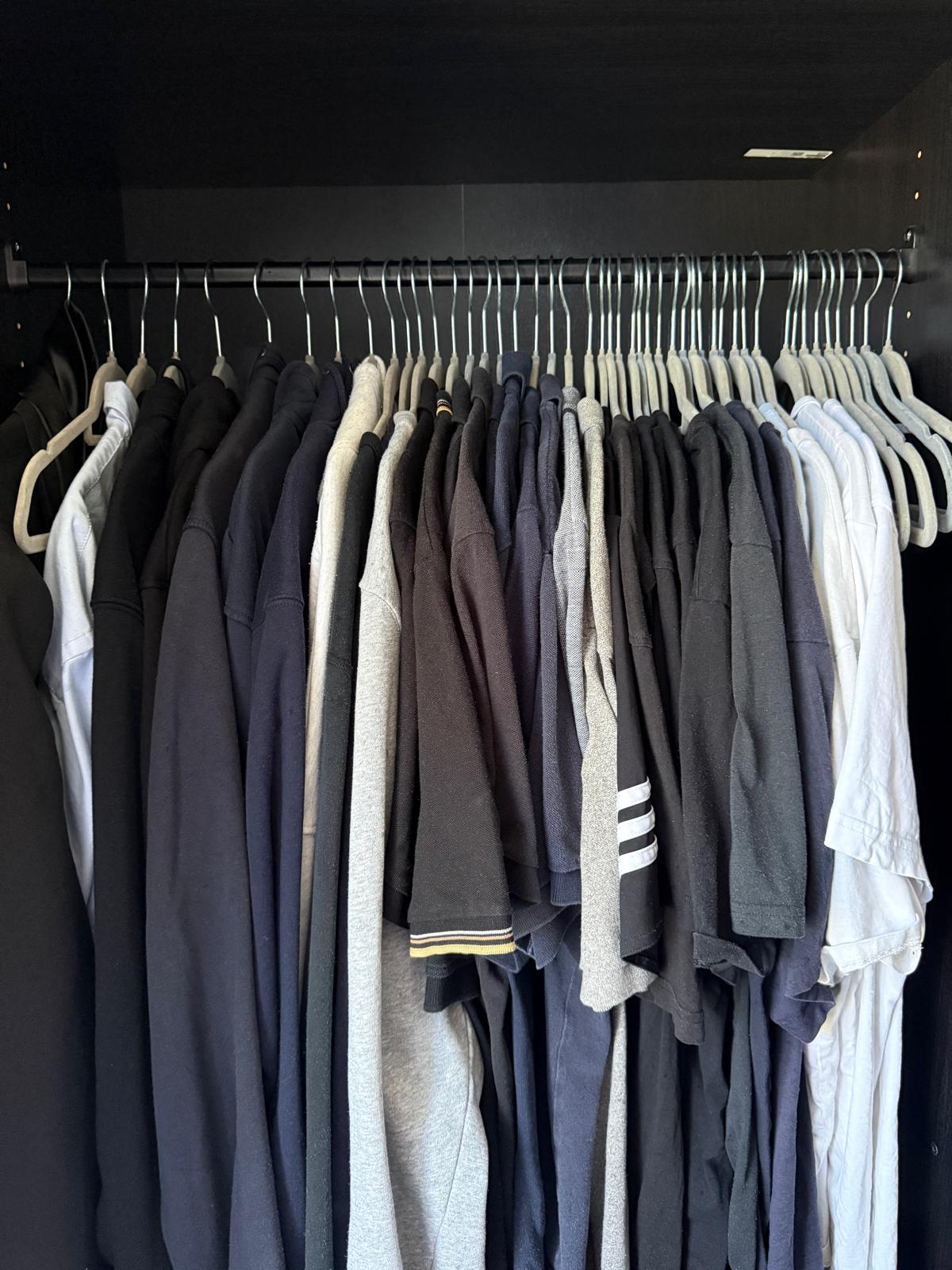 Wardrobe rail after organising, with tops on matching hangers and grouped by colour