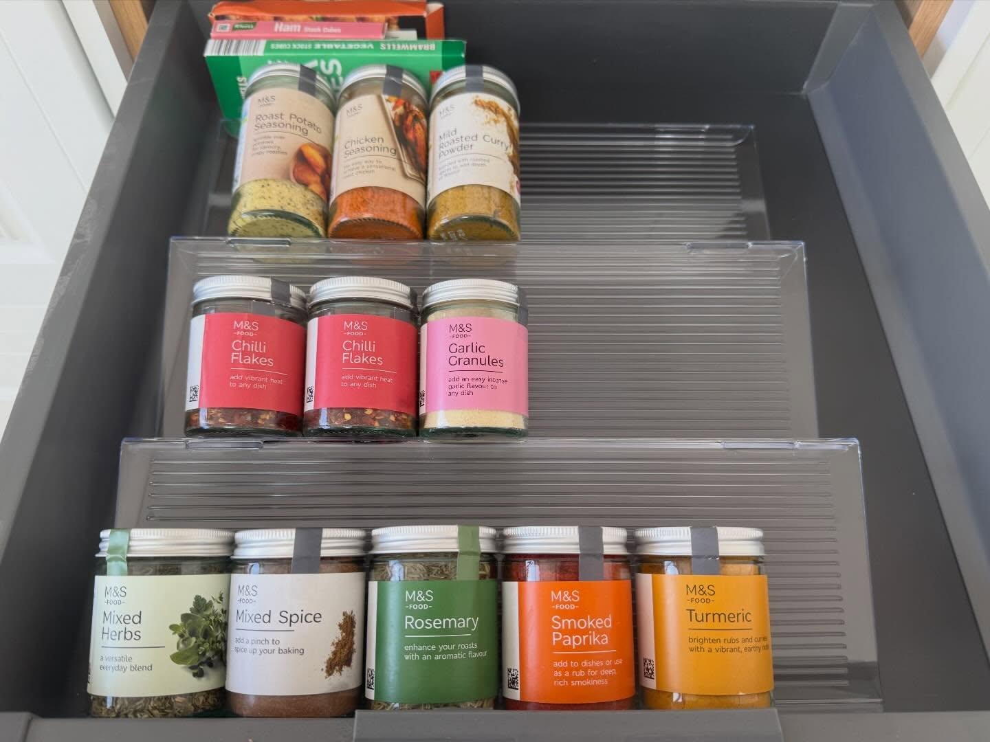 Spice drawer after organising, with jars decanted and tiered in clear risers