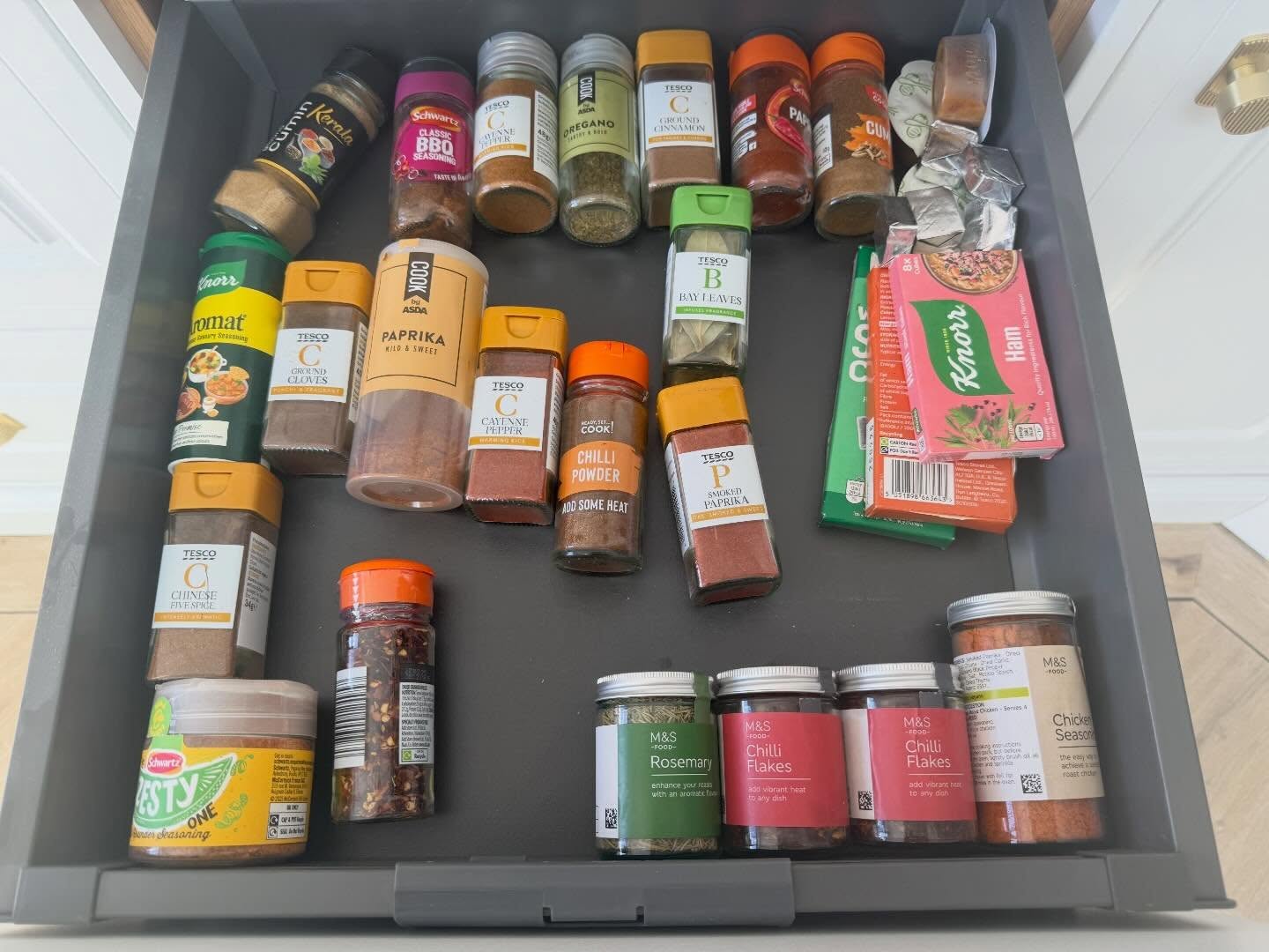 Kitchen spice drawer before organising, with jars and packets crowded together