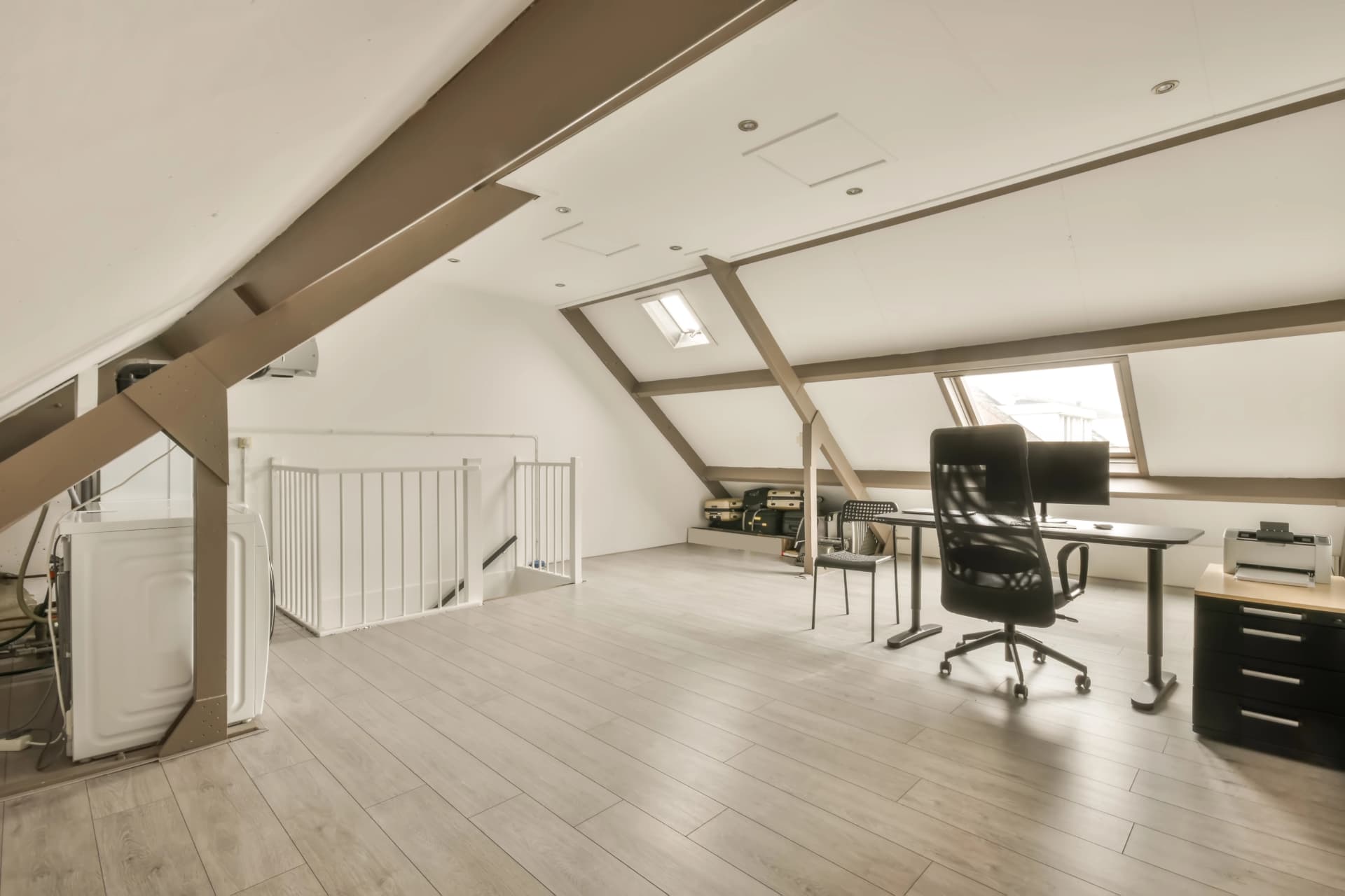 Spacious converted loft with exposed beams, clear floor space and a tidy desk area under the skylights