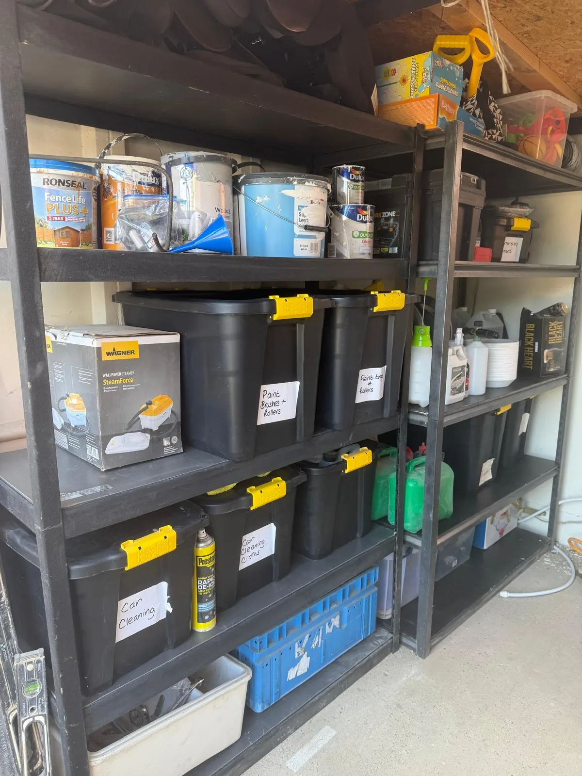 Garage shelving after organising, with labelled lidded boxes for paint, car cleaning and DIY