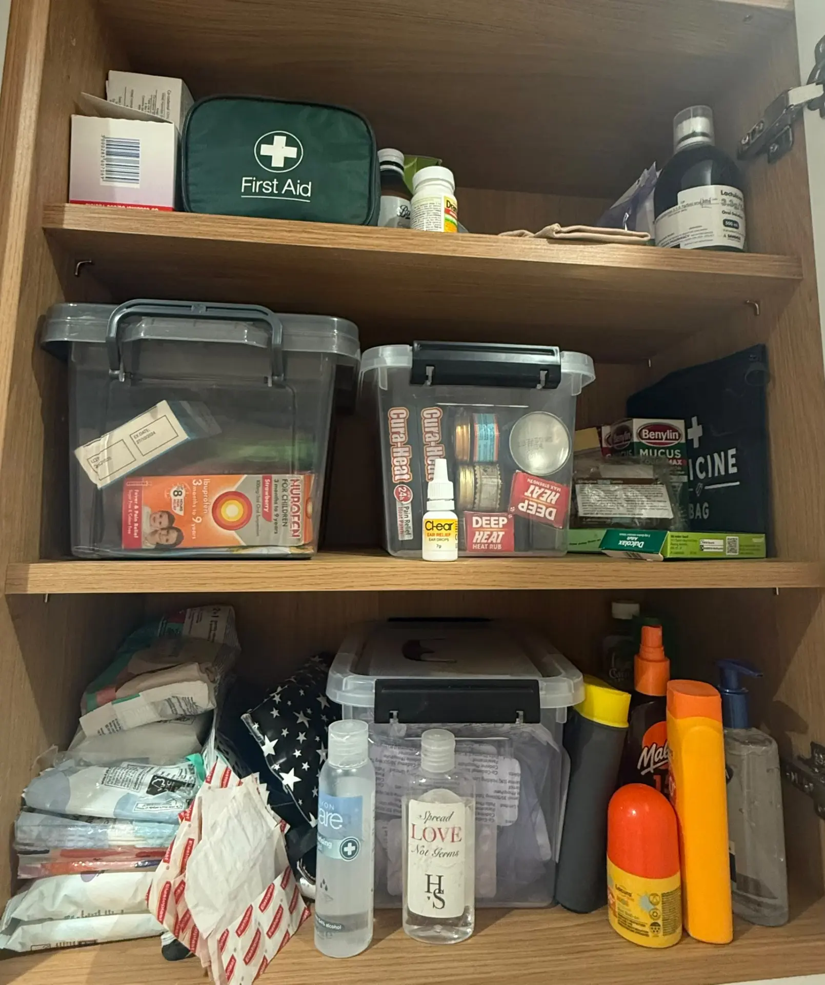 Family medicine cupboard before organising, with loose boxes and bottles across the shelves